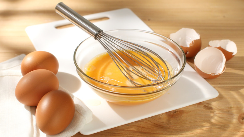 Whisked raw eggs in glass bowl