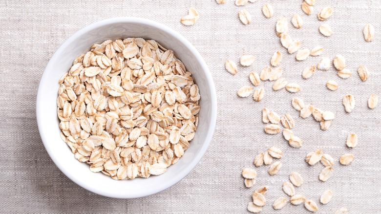 Overhead shot of rolled oats in a white bowl on linen