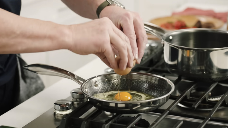 Gordon Ramsay cracks egg into pan.