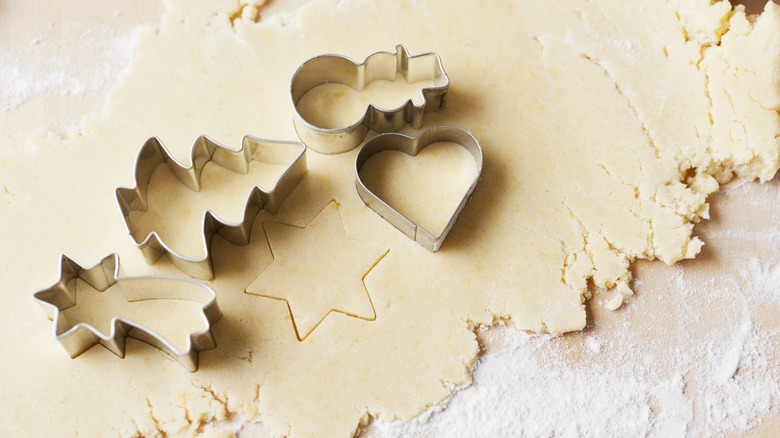 Cookie cutters sitting on top of sugar cookie dough.