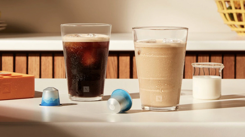 Two iced coffee drinks on a kitchen counter with Nespresso pods