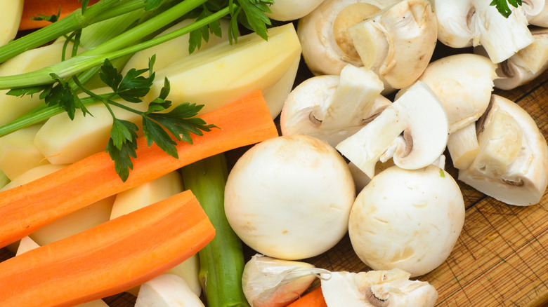 Vegetable soup ingredients including stalks of celery, carrots, and mushrooms
