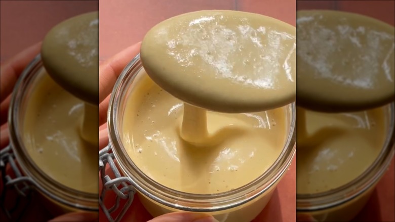 Whipped honey drizzling from a spoon to a jar