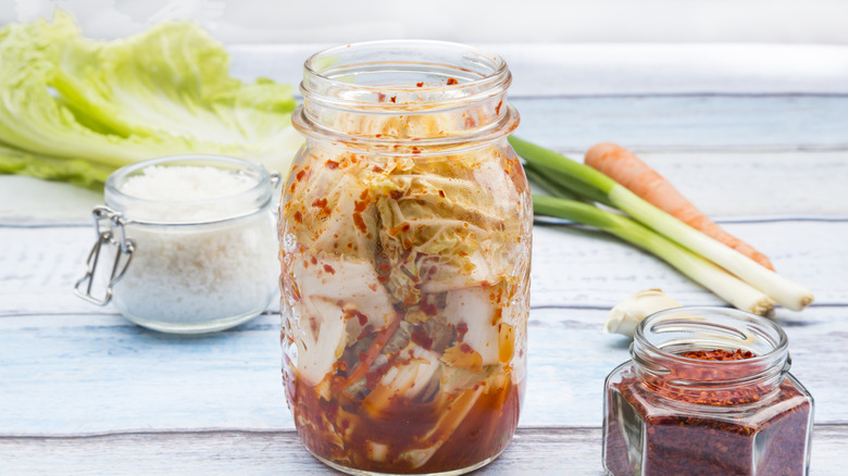 A jar of homemade kimchi with salt, chili flakes, chive and carrot.