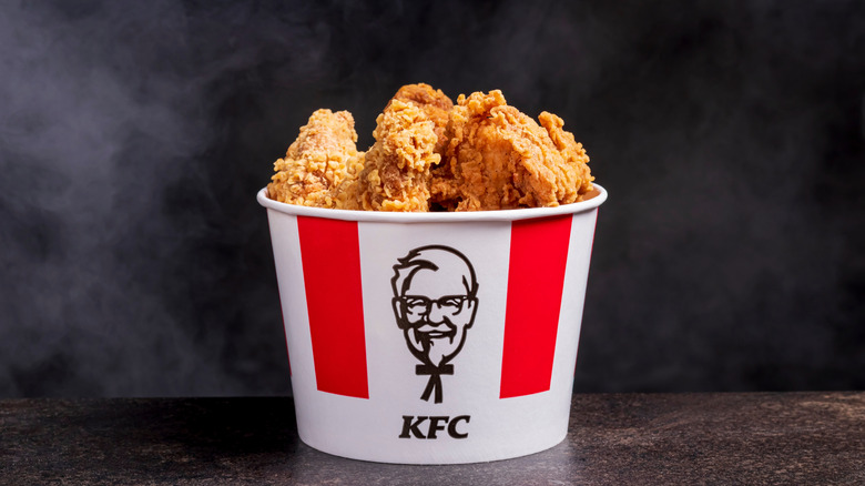 A bucket of KFC chicken on a black background.