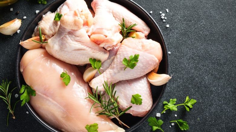 Raw chicken in a cast iron pan with herbs