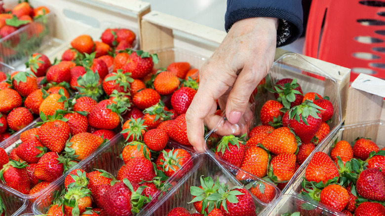 woman picking container of strawberries at the supermarket
