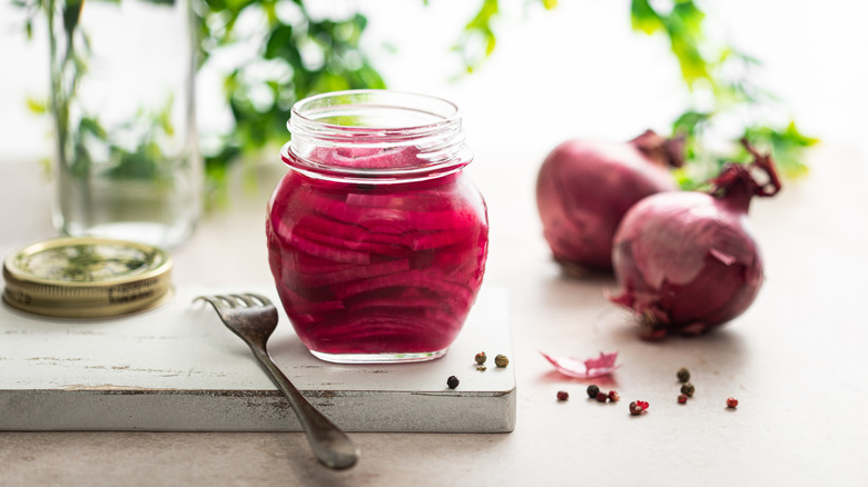 Pickled red onions suspended in a glass jar.