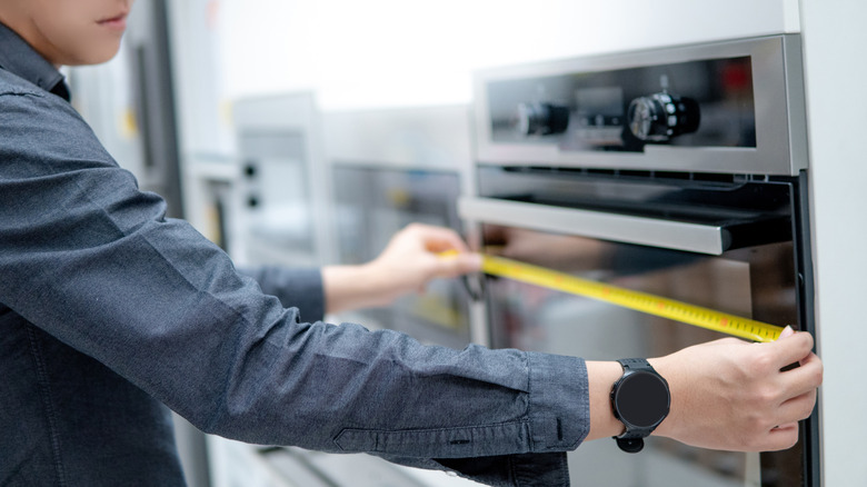 A shopper measures a range at an appliance store.