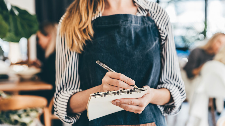 A server takes an order on a notepad