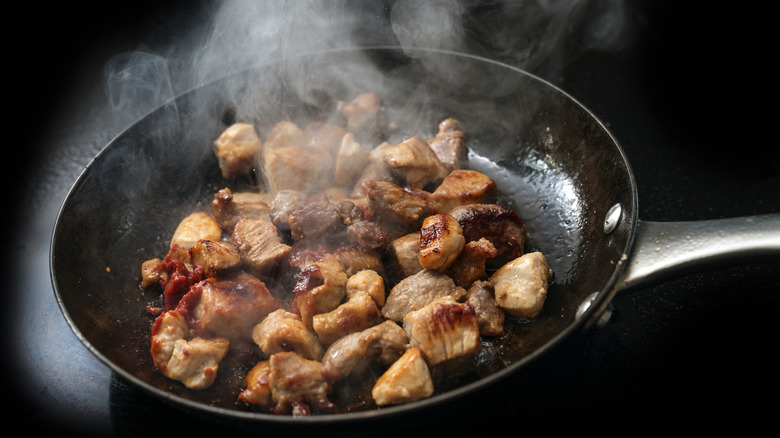 Meat searing in a hot black pan