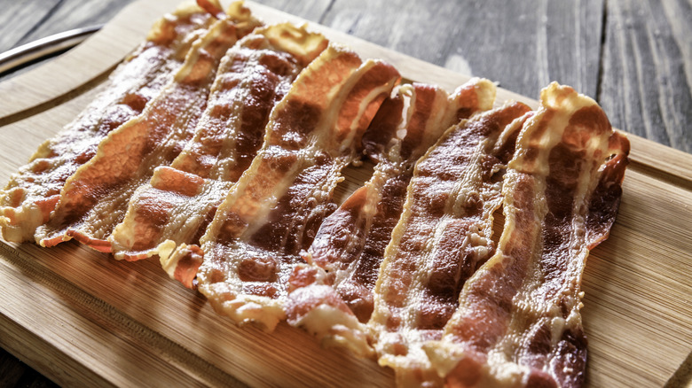 Cooked crispy bacon strips on a wooden board