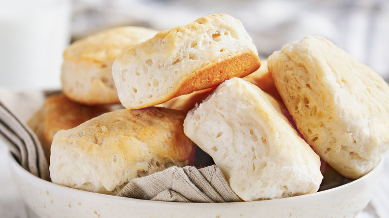 Flaky buttermilk biscuits in a bowl with a linen tea towel