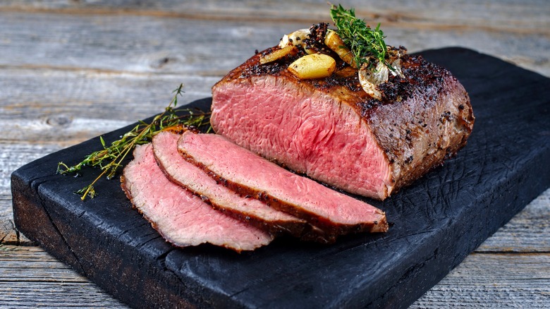 Roast beef sliced on black cutting board