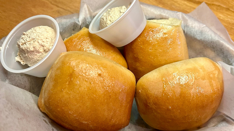 Texas Roadhouse rolls in a basket with small containers of cinnamon honey butter