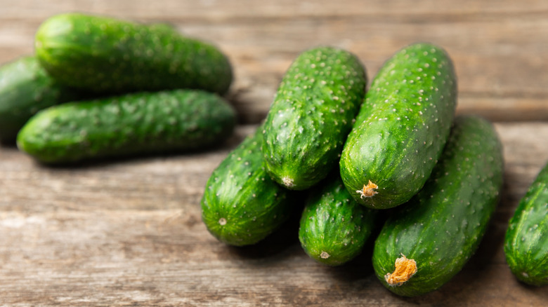 Wax-free pickling cucumbers stacked on a wooden table
