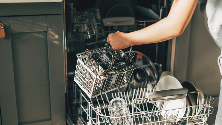 Someone removing the utensils basket from the dishwasher