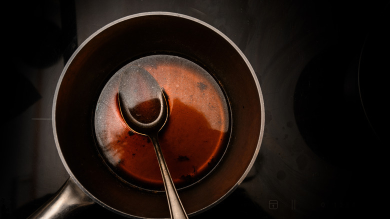 Red wine sauce in a metal pot with a spoon