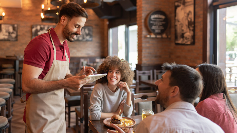 A restaurant server taking an order at a table of guests