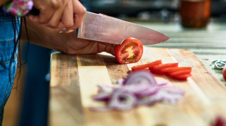 A woman slicing a tomato on a cutting board