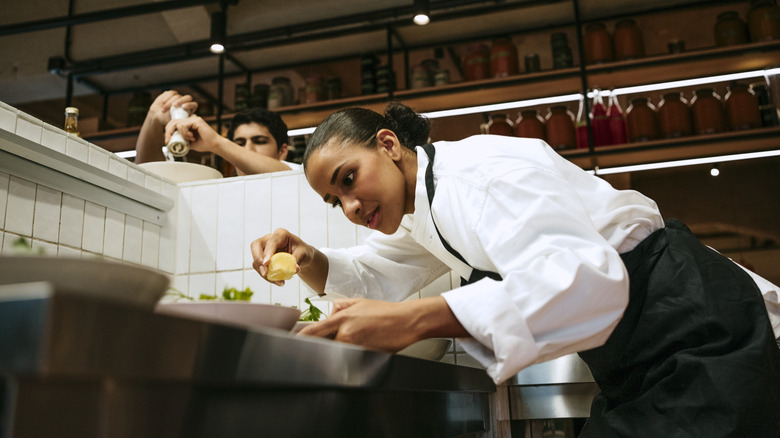 Professional chefs applying a citrus garnish to a dish