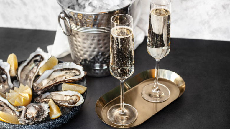 Two glasses of champagne, ice bucket, and tray of oysters