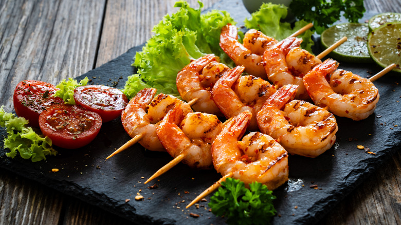 grilled shrimp on skewers next to lettuce and tomatoes