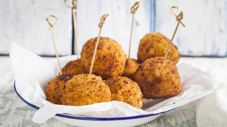 A plate of fried rice balls with toothpicks on parchment