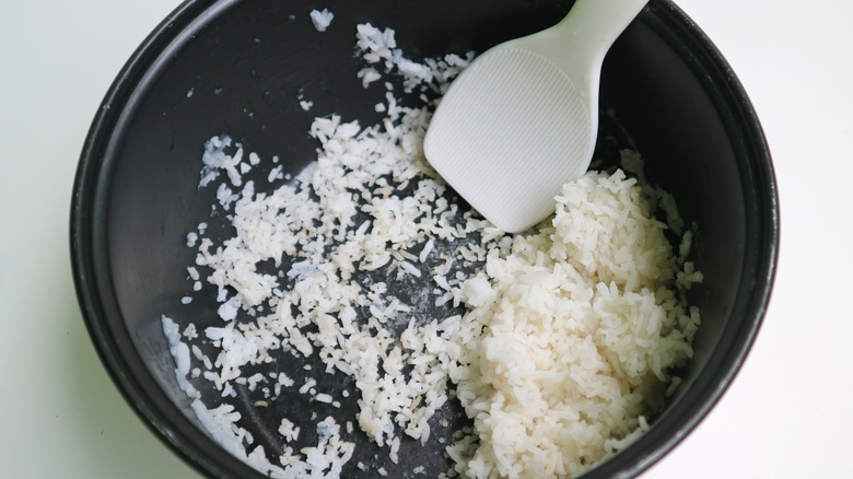 Leftover cooked white rice in a bowl with a plastic spatula