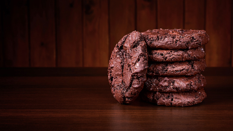 Double chocolate cookies piled on top of one another in a dark room