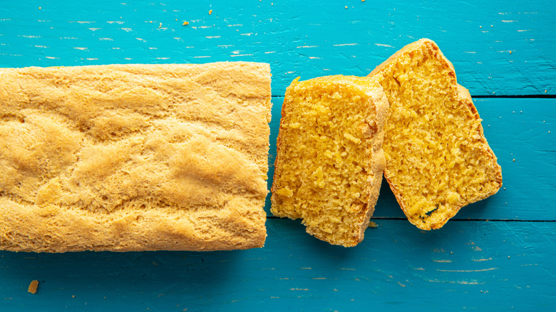 Cornbread loaf with 2 slices cut on blue surface