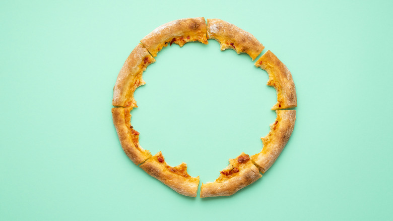 Pizza crusts arranged in a circle on a teal background