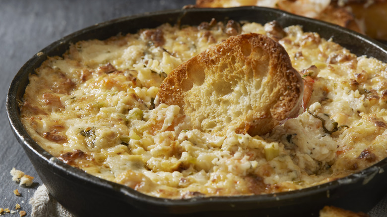 A large bowl of dip with melted cheese on top