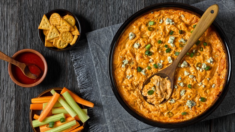 A large bowl of dip with accompaniments on the side