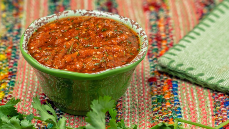 Salsa in green bowl on colorful placemat