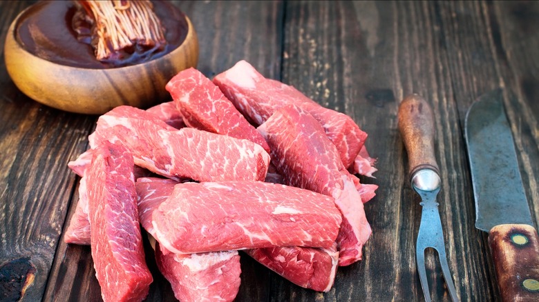 Raw pork ribs on wood table with mop brush in background