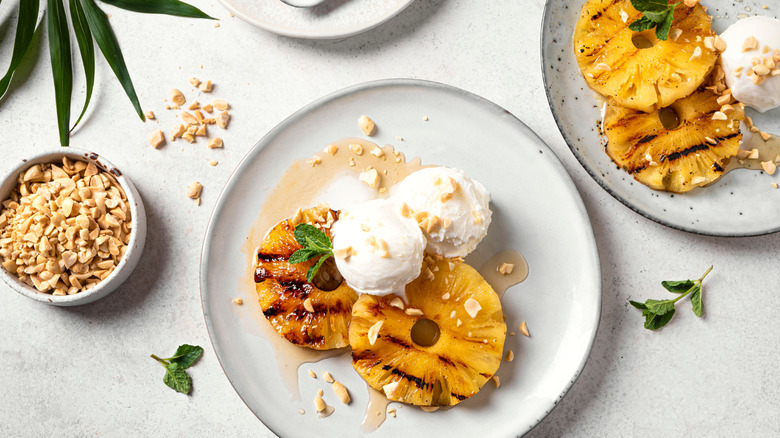 Grilled pineapple rings with ice cream, syrup, and chopped nuts