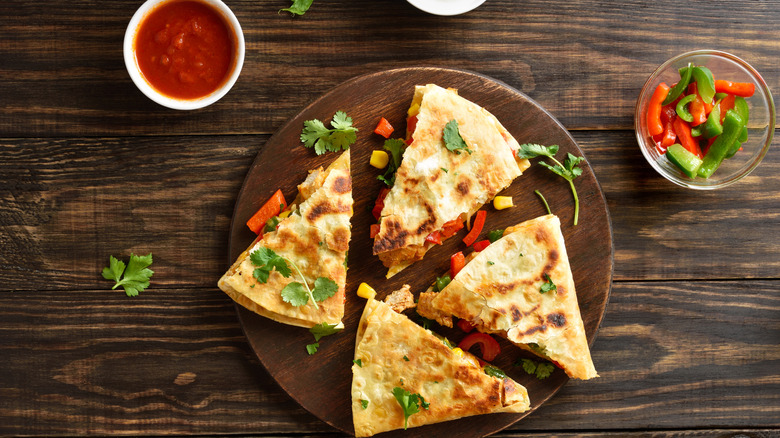 A cut quesadilla on a wooden plate