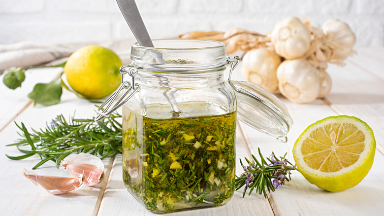 A jar of vinaigrette with fresh herbs