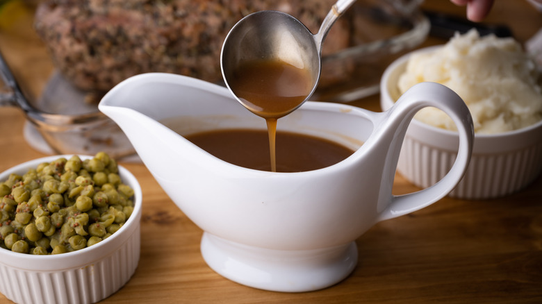 Brown gravy in a white gravy boat.