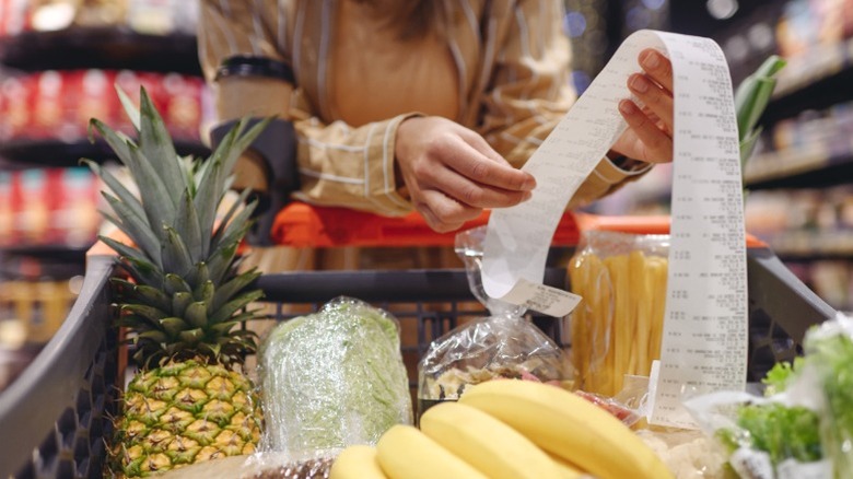 A woman shopping in a grocery store with her cart full of produce.