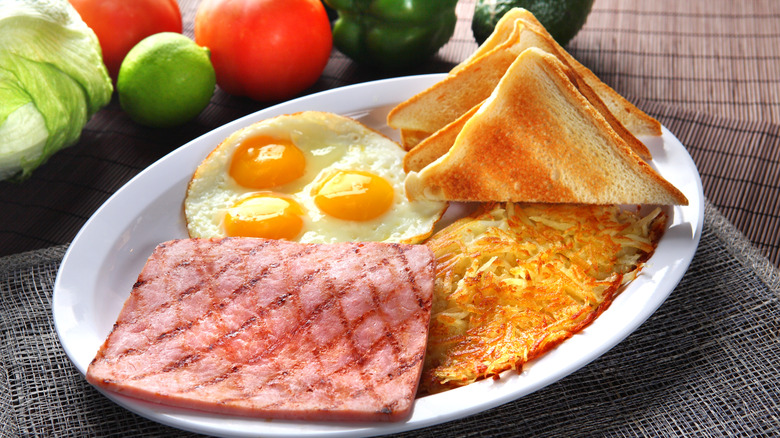 ham and eggs with toast on a white plate