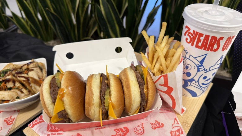 a lot of Smashed Jack Sliders in takeout box with side of fries and takeout cup