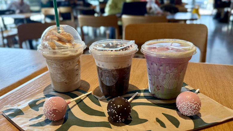 Three Starbucks drinks and cake pops lined up on table