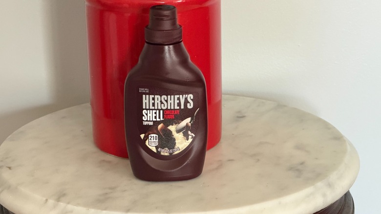 A bottle of Hershey's chocolate shell on a small table