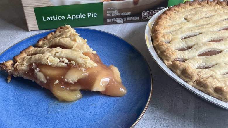 A slice of Marie Callender's Lattice Apple Pie on a blue plate next to the whole pie