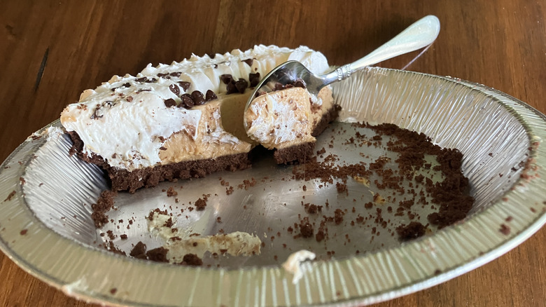 A spoon scoops up remnants of Marie Callender's Peanut Butter Cream Pie in a nearly empty aluminum pie tin