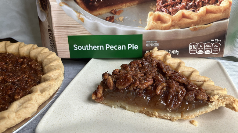 A slice of Marie Callender's Southern Pecan Pie next to its box and the rest of the pie in its tin