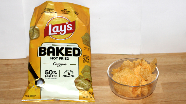 A bag of Lay's Baked Original potato chips beside a bowl full of chips