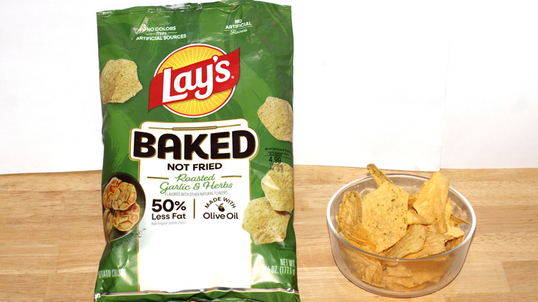 A bag of Lay's Baked Roasted Garlic & Herbs potato chips beside a bowl full of chips